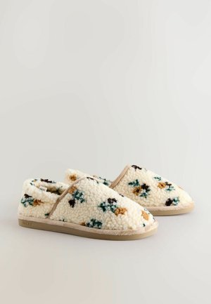 Krämsfärgade tofflor i fluffigt material med blommönster i blått, brunt och grönt. Har en beige gummisula och kant.