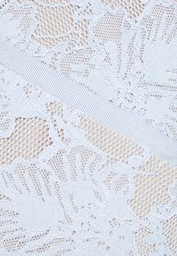 Ljusblå spetstyg med intrikata blommönster, en strukturerad nätbas och ett slätt elastiskt band som går diagonalt över.