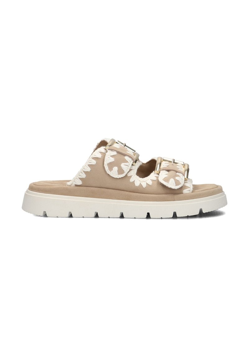Beige suede sandalen met twee gespen, voorzien van witte bloemenborduring aan de zijkanten en een chunky witte zool met profielpatroon.