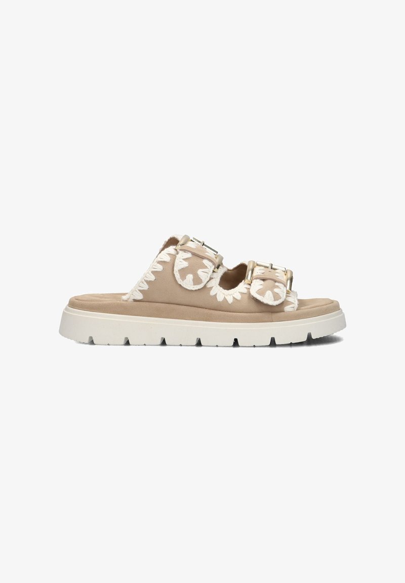 Beige suede sandals with two buckles, featuring white floral embroidery along the sides and a chunky white sole with tread pattern.