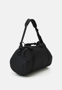 Black duffel bag made of textured fabric, featuring a round shape, adjustable shoulder strap, and zip closure with sturdy hardware.