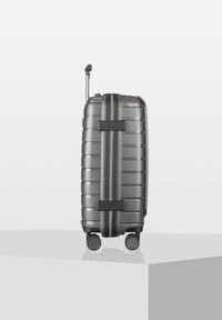 Valigia rigida di colore grigio scuro, con strisce testurizzate, manico estensibile e quattro ruote fluide per una facile mobilità.