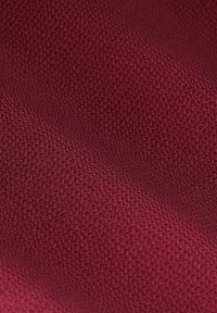 Tissu texturé couleur bourgogne avec un motif tissé, présentant une surface lisse et des variations subtiles d'ombre, transmettant une profondeur de couleur.