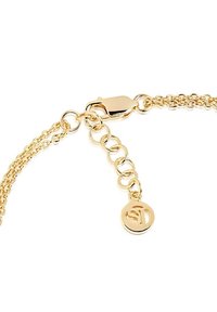 Guldpläterad kedjebror med sammanlänkade länkar, en säker kräftklo och en berlock med en stiliserad logotyp.