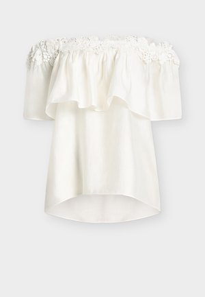 Hvid off-shoulder bluse med blomsterblondekant langs udskæringen samt løstsiddende, flagrende korte ærmer og krop.