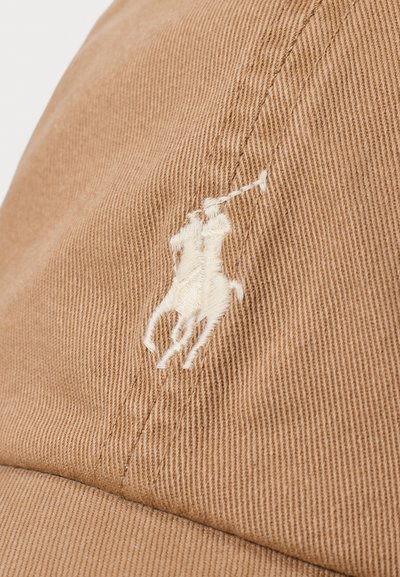 Rjava bombažna baseball kapa z teksturirano površino. Na sprednji strani je belo vezeno logotip polo igralca.
