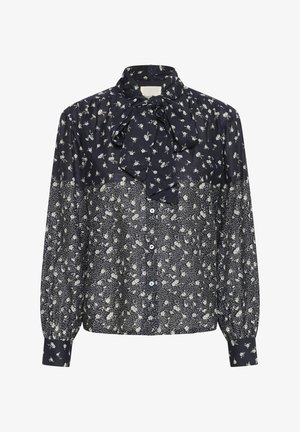 Tengerészkék blúz fehér virágmintával, hosszú puffos ujjak, gombos elülső rész és megkötött masni a magas gallérnál.