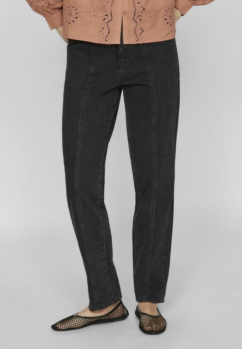Jeans de denim negro con un diseño de pierna recta, que presentan costuras frontales y una textura suave. Combinados con planos de malla negros.