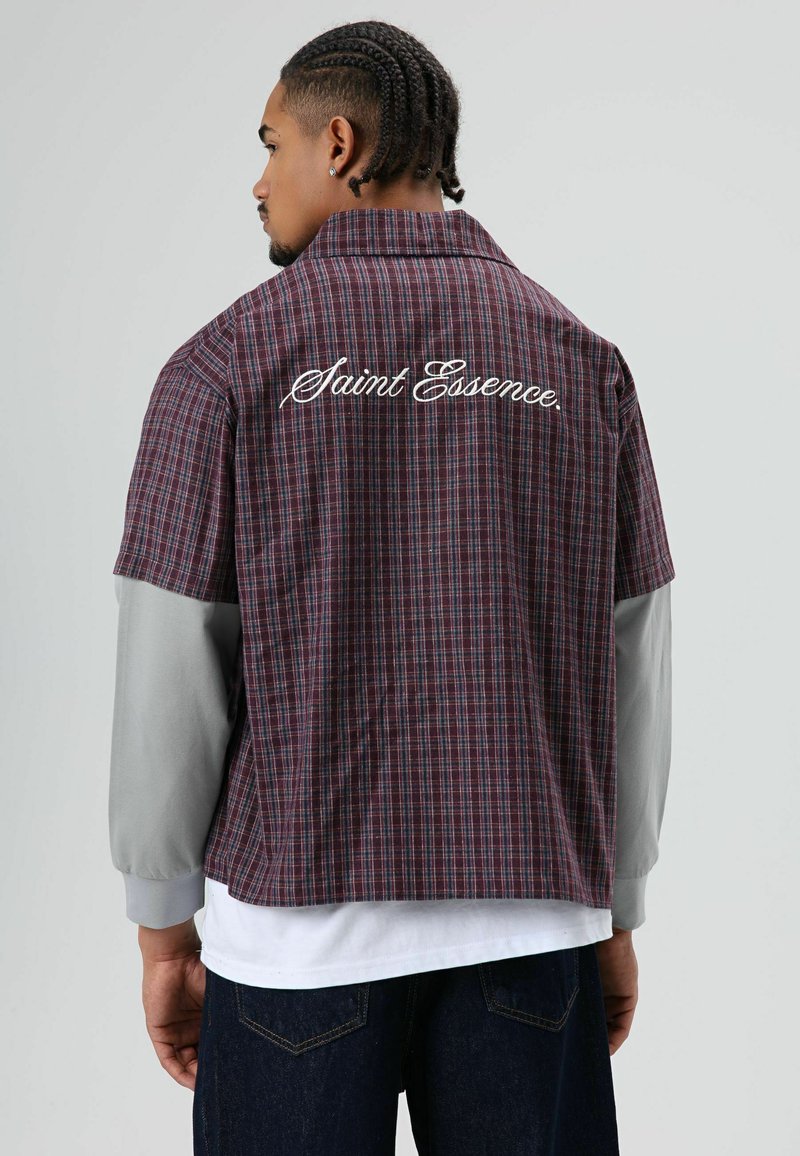 Chemise à manches courtes à carreaux en bordeaux et gris ; comporte un texte brodé « Saint Essence » dans le dos ; coupe décontractée avec une forme ample.