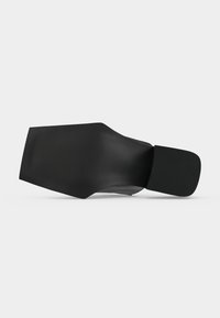 Chaussure noire à large bout carré et talon plat bloc, vue par la semelle sur un fond uni clair.