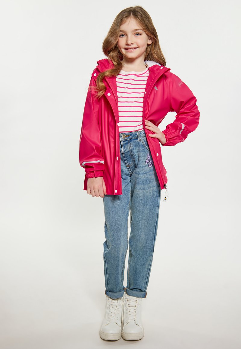 Rožinė nepralaidi vandeniui striukė su kapišonu, balta ir raudona dryžuota marškinėliai po ja, aukštu liemeniu džinsai su drugelių siuvinėjimu ir baltos sportbačiai.