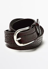 Cintura di pelle marrone scuro con motivo coccodrillo, arrotolata con fibbia metallica curva color argento su sfondo bianco.