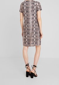 Robe à manches courtes avec un imprimé serpent rose et noir; tissu léger, coupe décontractée, longueur genou, associée à des sandales à talons carrés noires.