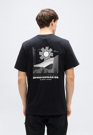 Zwart katoenen T-shirt met een grafisch ontwerp van een zon, landschap en tekst op de achterkant. Korte mouwen en een losse pasvorm.