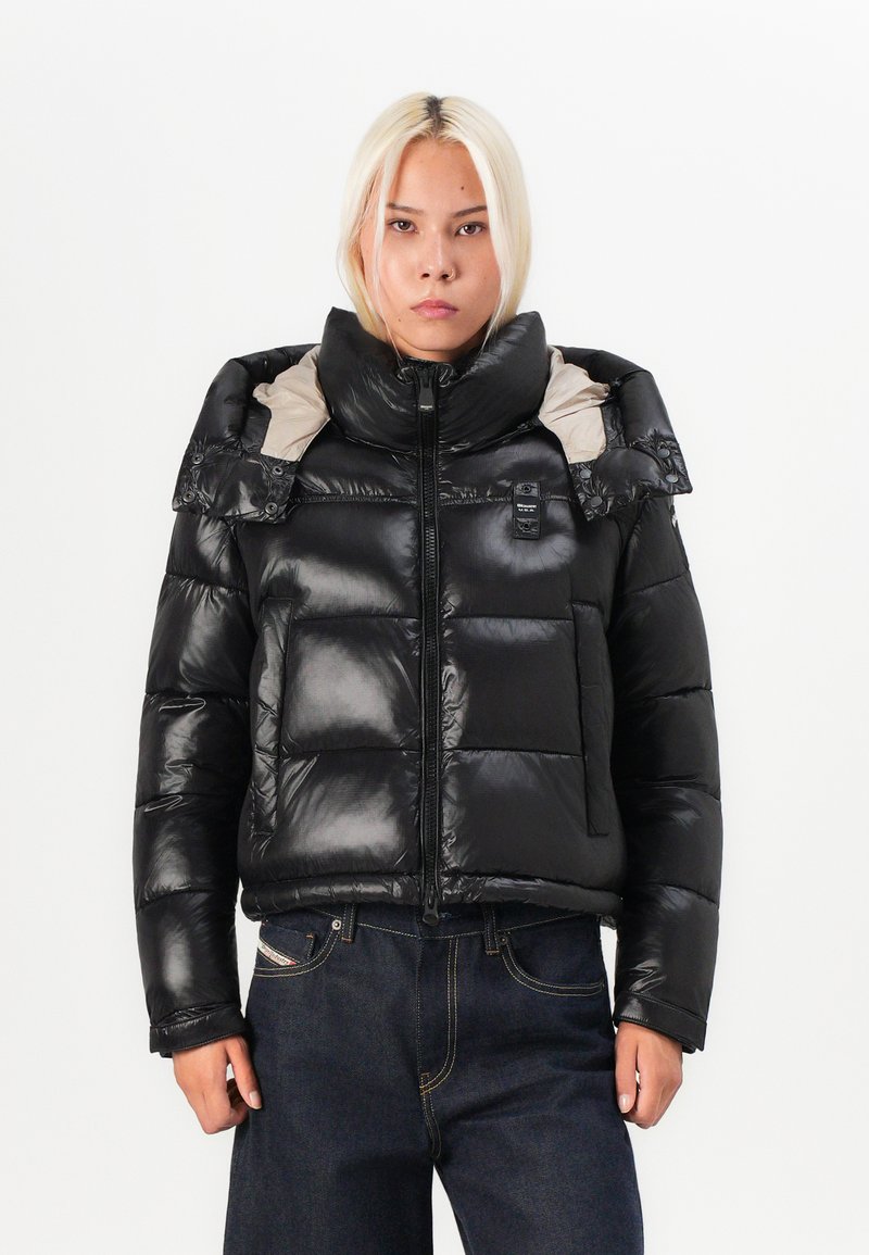 Schwarze Daunenjacke mit glänzender Oberfläche, hohem Kragen und hellgrauem Innenfutter. Verfügt über große gesteppten Abschnitte und einen Frontreißverschluss.