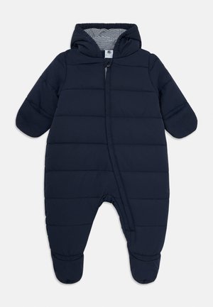 Combinaison de neige pour bébé matelassée bleu marine avec une fermeture éclair à l'avant, des poignets côtelés et une doublure de capuche rayée. Comprend une texture matelassée et un design avec pieds.