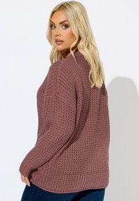 Vaffelstickad tröja i mauve, med avslappnad passform, långa ärmar och rund halsringning. Mjuk textur och subtila ribbade detaljer syns.