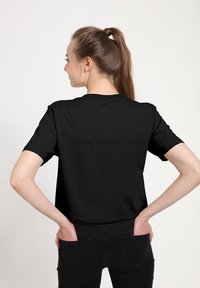 Czarny t-shirt z krótkim rękawem i okrągłym dekoltem, wykonany z bawełny. Tkanina jest gładka i elastyczna, zapewnia wygodne dopasowanie.