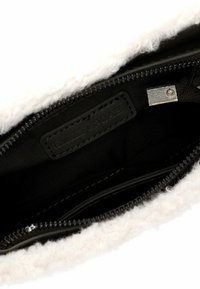 Borsa nera con zip, rifinita con un morbido pelo bianco, dotata di un interno liscio, dettagli cuciti e un'etichetta in pelle nera.