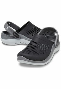 Czarno-szare klapki Crocs z perforowanym wzorem, elastycznym materiałem, okrągłym noskiem oraz solidnym paskiem na pięcie dla pewnego trzymania. Gumowa podeszwa.