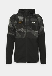 Sudadera con cremallera negra, con una parte superior de camuflaje gris texturizado, capucha ajustable con cordones y un pequeño logo en el pecho. Cuenta con bolsillos laterales.