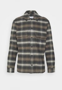 Brun och svart rutig skjorta med långa ärmar, knappstängning, två bröstfickor och krage. Tillverkad av texturerat tyg.