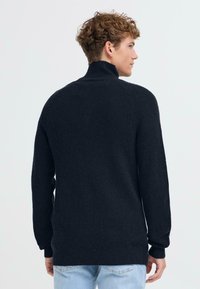Maglione a coste navy con colletto alto, maniche lunghe e vestibilità rilassata. Presenta un tessuto texturizzato e un orlo dritto.