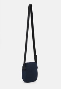 Borsa a tracolla blu navy in tessuto, di forma rettangolare, con fascia nera regolabile con il marchio 'TOMMY JEANS' e chiusura a zip.