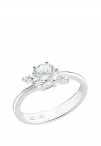 Anello d'argento con un grande diamante rotondo centrale e due piccoli diamanti rotondi su ciascun lato, su uno sfondo bianco.
