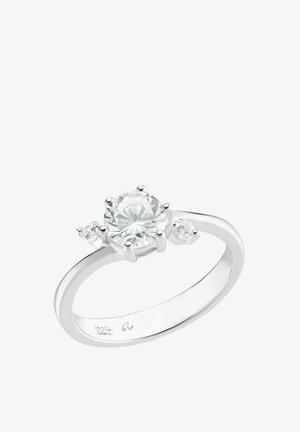 Silberring mit einem großen zentralen runden Diamanten und zwei kleineren runden Diamanten auf jeder Seite vor einem weißen Hintergrund.