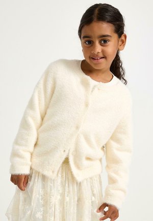 Roomwitte, fluffy cardigan met een ronde hals, knoopsluiting en ribgebreide manchetten, gedragen over een doorzichtige, gebloemde rok.