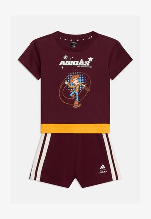 Bordowy strój dziecięcy Adidas z żółtą lamówką, z Woodym z filmu Toy Story na koszulce i paskami Adidas na szortach z logo Pixar.