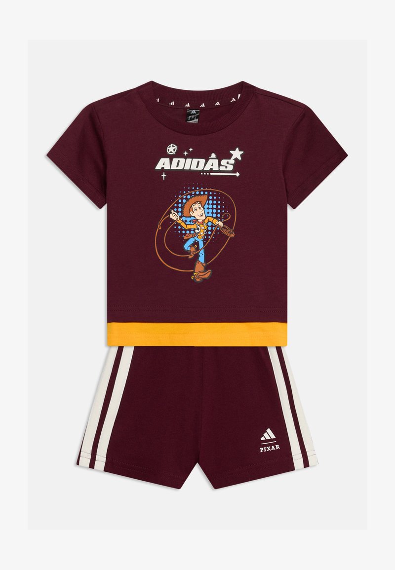Tenue Adidas pour enfants bordeaux avec bordure jaune, avec Woody de Toy Story sur le t-shirt et les bandes Adidas sur le short avec le logo Pixar.