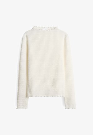 Cream-colored long-sleeve top with textured waffle knit fabric and lettuce edge details on collar, cuffs, and hem.