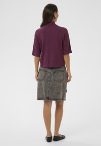 Maroon short-sleeve top paired with a gray denim skirt featuring front pockets, visible stitching, and a straight cut. Black flat shoes complete the look.