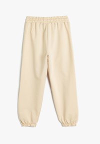 Helle beige joggebukser laget av mykt stoff. Elastisk liv og mansjetter. Har sidelommer og en avslappet passform. Glatt tekstur.