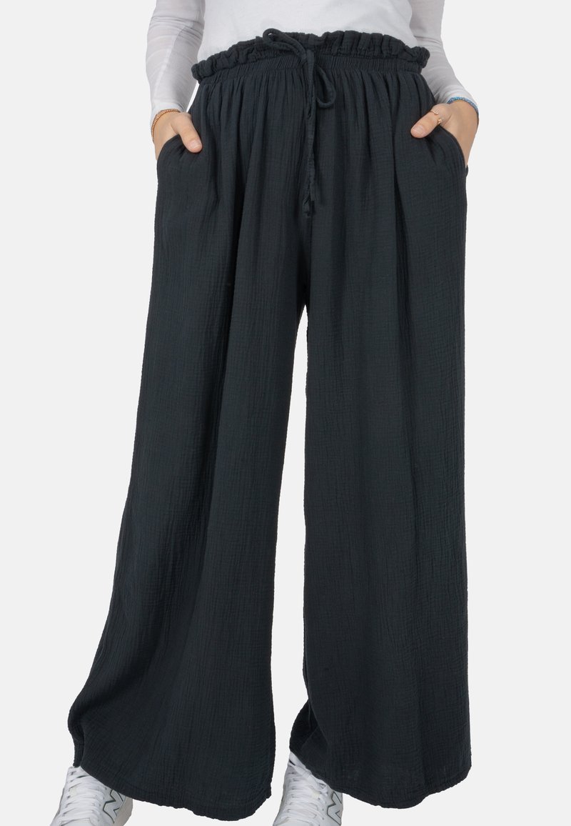 Pantalons larges en tissu noir texturé avec une taille élastiquée, un détail à cordon de serrage et des poches latérales.