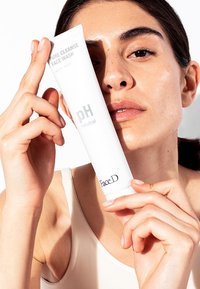 White tube of face wash held by a person, featuring the text "Pure Cleanse Face Wash" and "pH neutral," smooth surface, simple design.