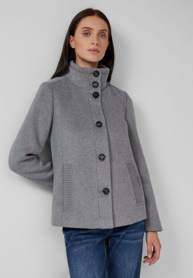 Grijze wolmix jas met hoge kraag, zeven zwarte knopen, zijzakken met ribbeldetails en een gestructureerde, op maat gemaakte pasvorm.