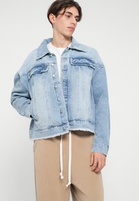 Jachetă din denim decolorat cu o guler clasic, buzunare frontale și închidere cu nasturi. Dantelă scurtă cu margini nepărăsite și o croială supradimensionată.