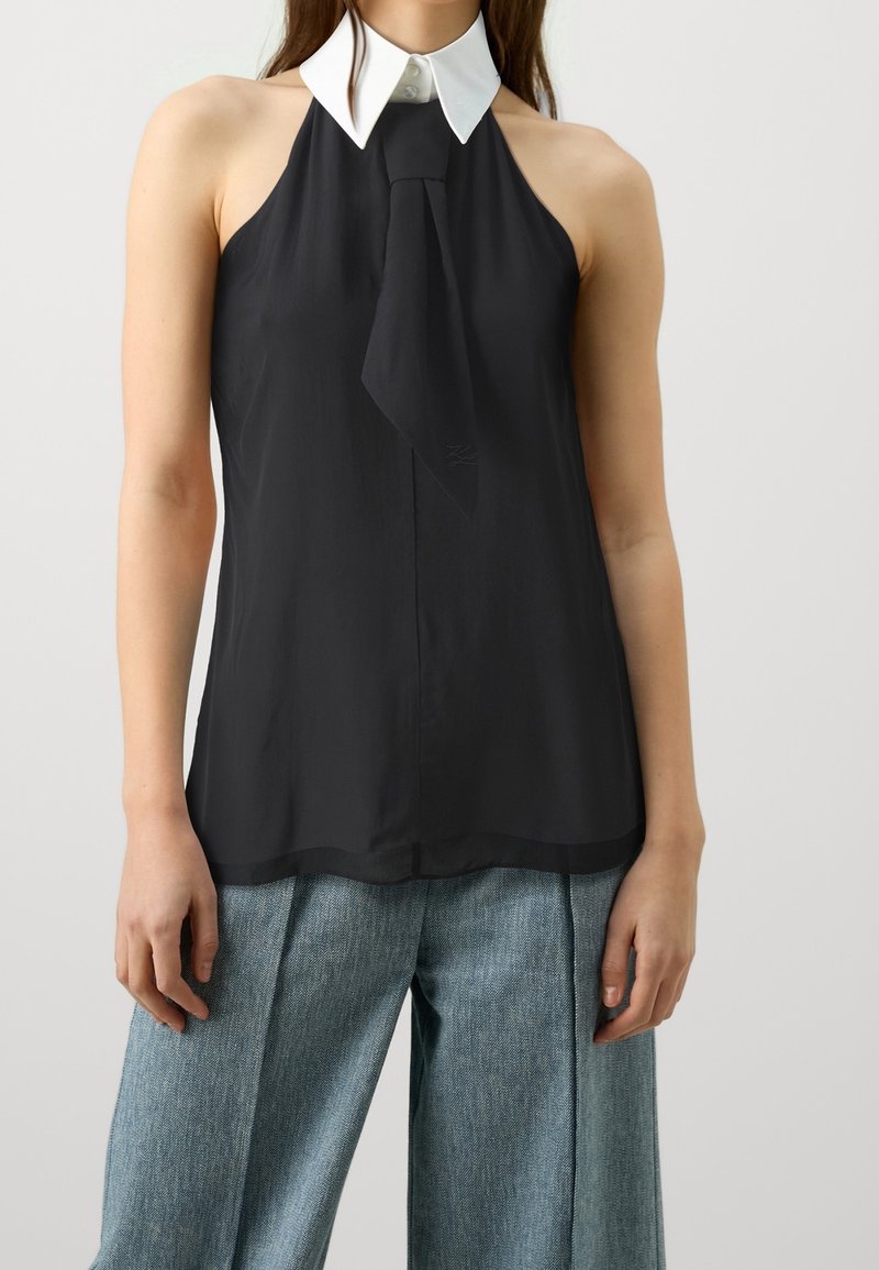 Black halter neck top with a white collar and a tie detail at the front. Smooth fabric, simple silhouette, and a straight hem.