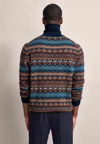 Strickpullover mit einem mehrfarbigen geometrischen Muster in Brauntönen, Blau und Orange. Hoher Kragen und gerippte Bündchen. Strukturiertes Finish.