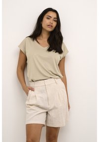 Beige V-hals T-shirt gecombineerd met licht beige geplooide shorts, gemaakt van een zachte stof, met zijzakken en een relaxed fit.