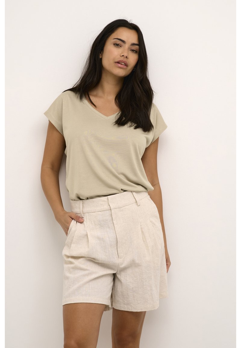 Beige V-hals T-shirt gecombineerd met licht beige geplooide shorts, gemaakt van een zachte stof, met zijzakken en een relaxed fit.