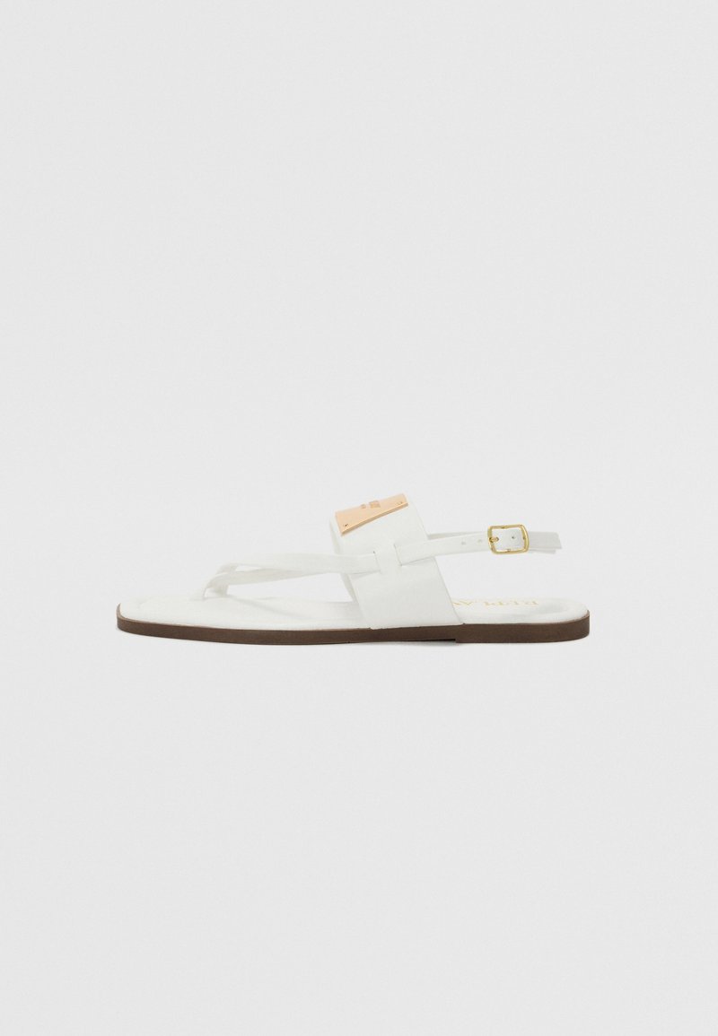 Vita flip-flopsandal med platt sula och smal rem. Har en guldaccent på ovansidan och en brun sula för kontrast.