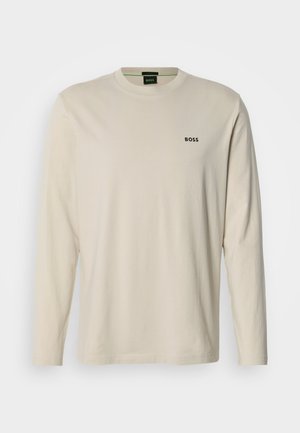 Langærmet beige T-shirt lavet af bomuld, med rund halsudskæring og et lille sort "BOSS"-logo på venstre bryst. Glat tekstur.