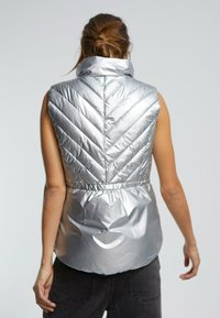 Zilveren puffervest met een hoge kraag, voorzien van chevron-quilting, elastische taille en een gladde, glanzende textuur. Zonder mouwen; achteraanzicht getoond.