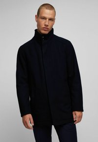 Marineblauwe wollen jas met hoge kraag, een sluiting met knoppen aan de voorkant, zijzakken en een minimalistisch ontwerp, met een gladde textuur en een getailleerde pasvorm.