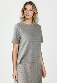 Grijze en blauwe gemusterde top met korte mouwen, een ronde halslijn, een relaxte pasvorm en een gladde textuur, gecombineerd met een bijpassende rok tot onder de heupen.