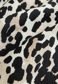 Tessuto a stampa leopardo con una superficie testurizzata, caratterizzata da grandi macchie nere e beige in un materiale morbido e tessuto.